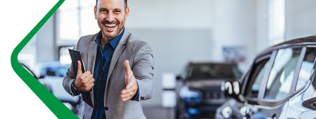 Castrol Auto Film representative greeting a customer with cars in the background.